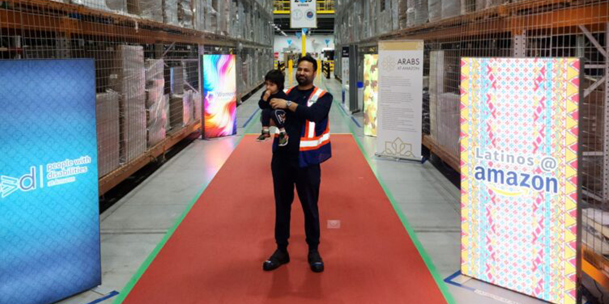 Ash Gill holding child while standing with Amazon signs