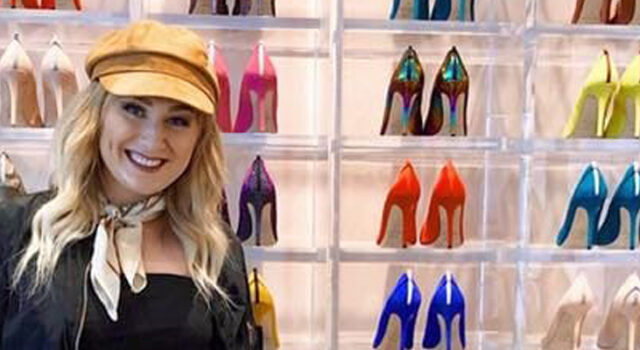A photo of Kayla Kruse in front of a wall displaying high heels in different colors