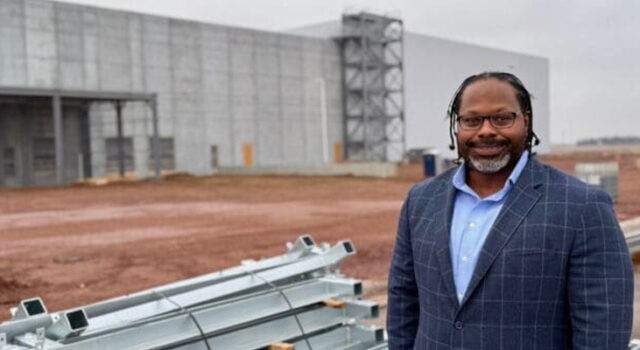 A photo of Sam Douglas in front of a building project